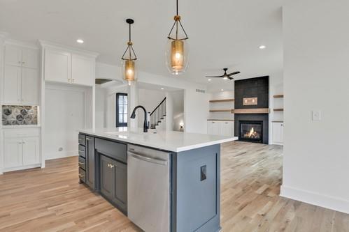 kitchen with white cabinets, dishwasher, light countertops, a ceiling fan, and light wood finished floors