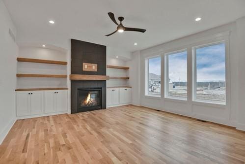 unfurnished living room featuring a large fireplace, recessed lighting, a ceiling fan, and light wood-style floors