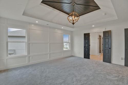 unfurnished room featuring a decorative wall, a raised ceiling, and carpet
