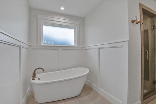 full bathroom with a decorative wall, a shower stall, and a freestanding tub