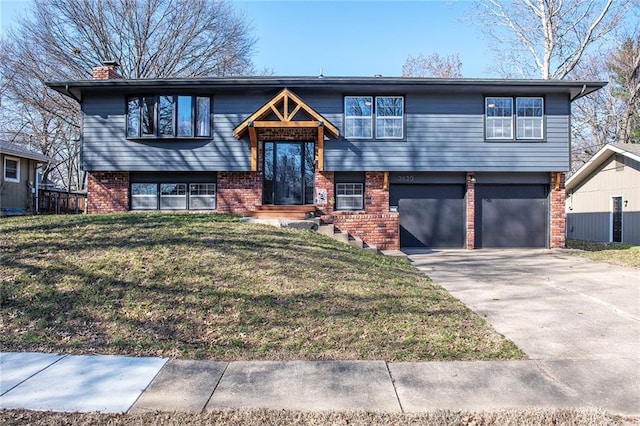 split foyer home featuring brick siding, driveway, a front yard, and a garage