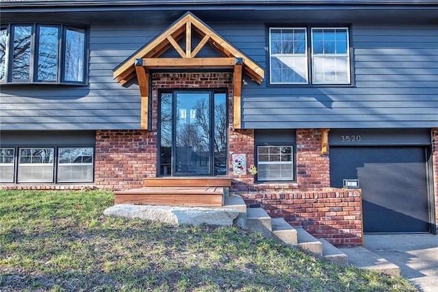 entrance to property featuring brick siding, concrete driveway, and a garage