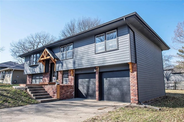 split foyer home featuring a garage, brick siding, and driveway