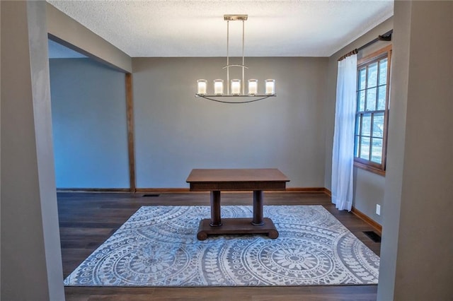 dining area featuring wood finished floors, baseboards, visible vents, a textured ceiling, and a chandelier