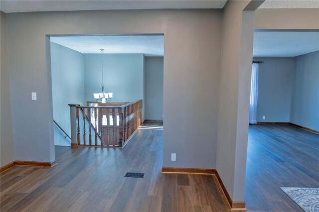 interior space featuring baseboards, an upstairs landing, an inviting chandelier, and wood finished floors