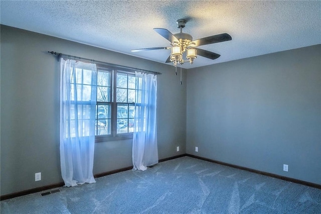 unfurnished room with baseboards, carpet, ceiling fan, and a textured ceiling