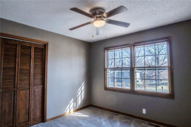 unfurnished bedroom featuring carpet, visible vents, baseboards, a closet, and a textured ceiling