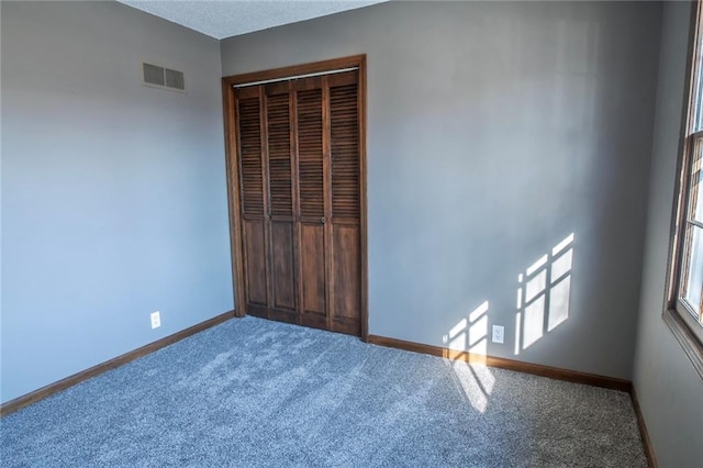 unfurnished bedroom featuring carpet flooring, baseboards, visible vents, and a closet