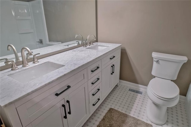 bathroom with a sink, toilet, and double vanity