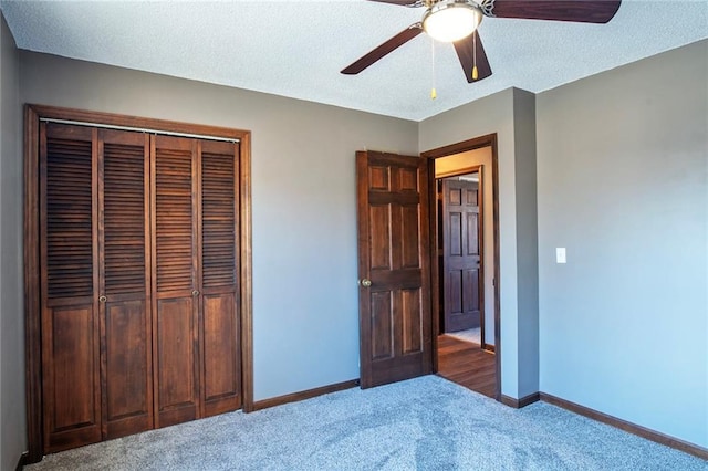 unfurnished bedroom with baseboards, carpet floors, ceiling fan, a closet, and a textured ceiling