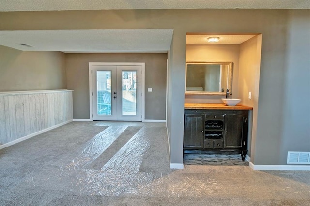 unfurnished living room featuring baseboards, french doors, visible vents, and a sink