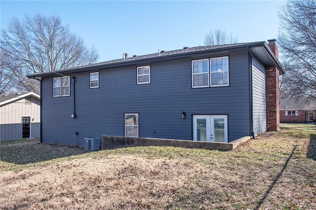 rear view of house featuring french doors, a yard, central AC, and a chimney