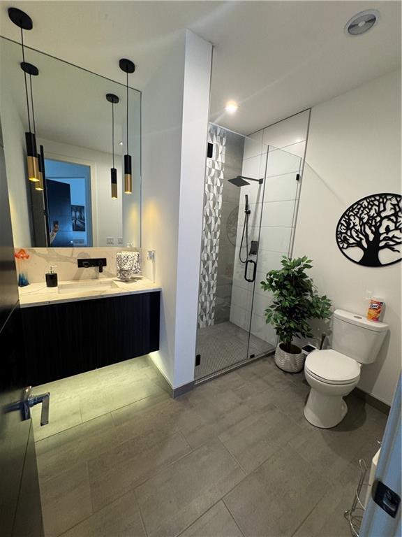 bathroom featuring a shower stall, toilet, vanity, and baseboards