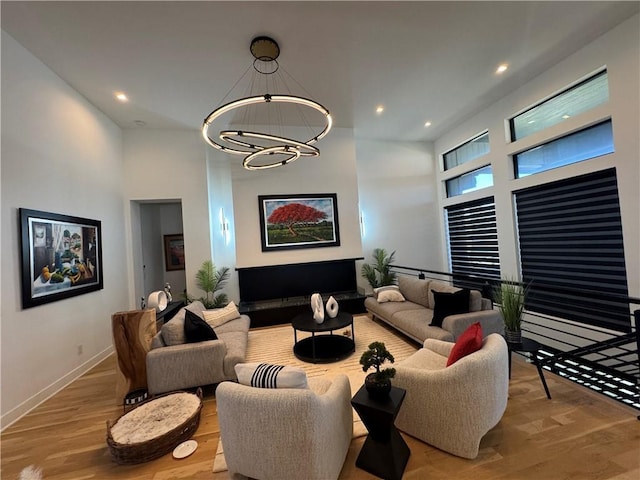 living area featuring a chandelier, recessed lighting, a towering ceiling, and wood finished floors