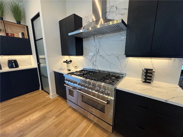 kitchen featuring range with two ovens, modern cabinets, dark cabinets, and wall chimney range hood