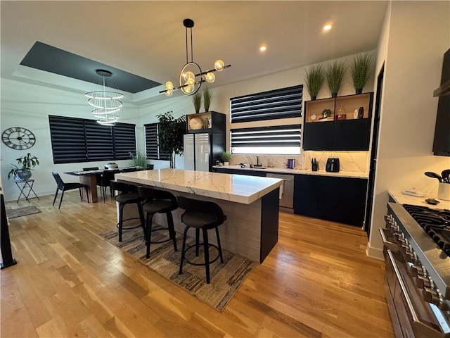 kitchen featuring light wood-type flooring, a notable chandelier, a kitchen breakfast bar, a kitchen island, and stainless steel appliances