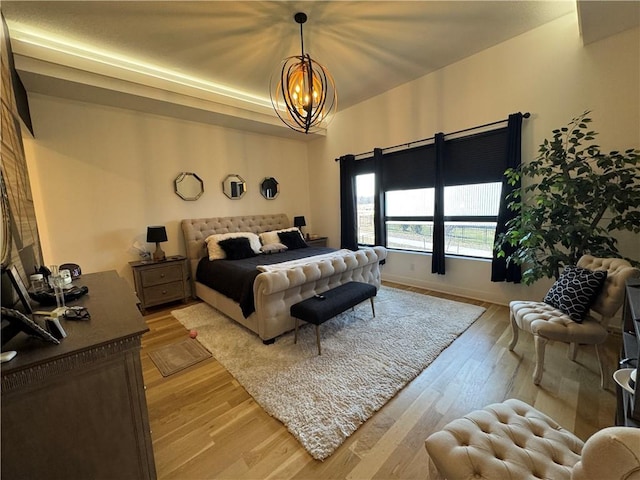 bedroom featuring baseboards, light wood-style floors, and an inviting chandelier