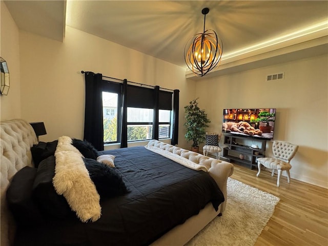 bedroom featuring a notable chandelier, wood finished floors, and visible vents