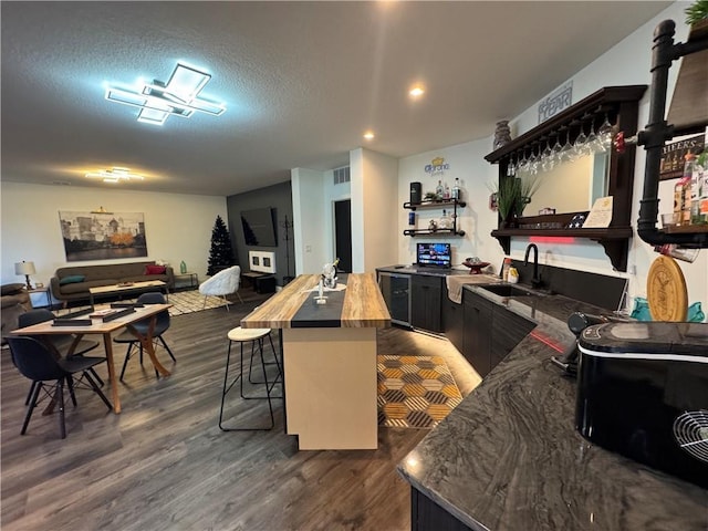 kitchen featuring open shelves, butcher block countertops, open floor plan, and a sink