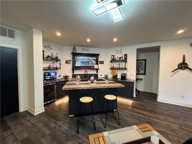 kitchen featuring visible vents, a center island, wine cooler, dark wood finished floors, and open shelves