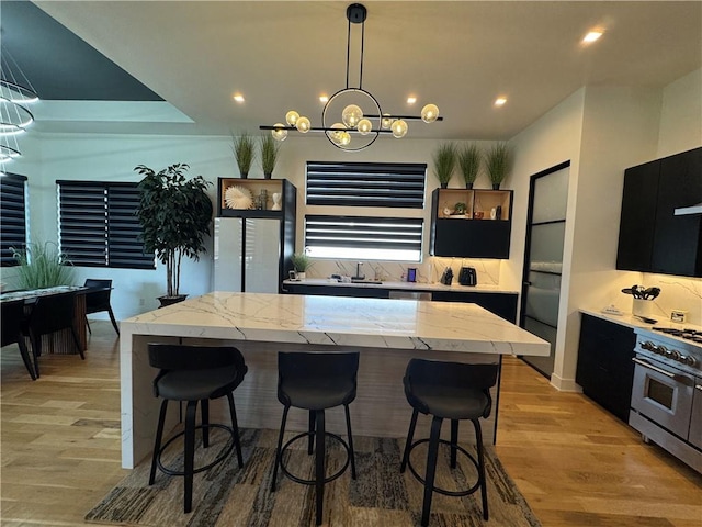 kitchen with a kitchen island, a breakfast bar, light wood-style floors, and high end stainless steel range oven