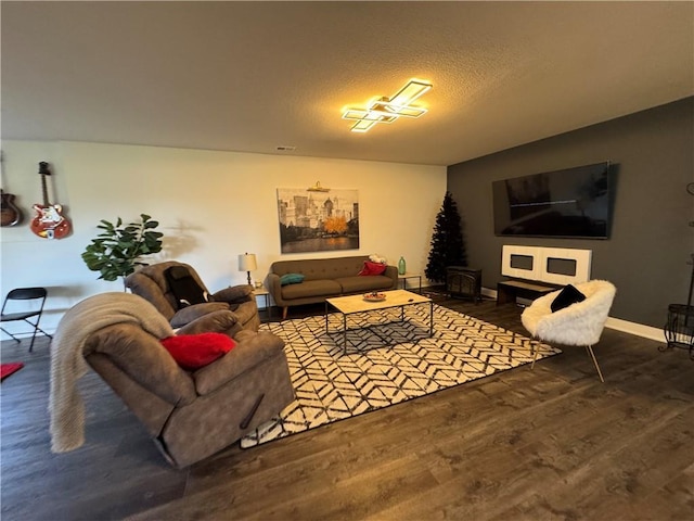 living room with visible vents, wood finished floors, baseboards, and a textured ceiling