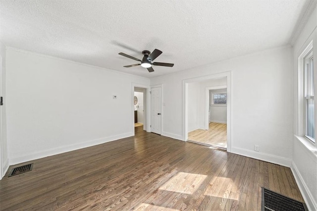 spare room with a textured ceiling, wood finished floors, visible vents, and ceiling fan