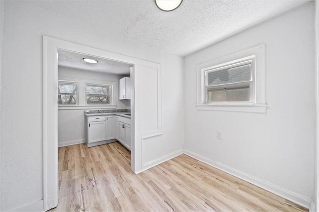 interior space featuring light wood-style flooring, baseboards, and a textured ceiling