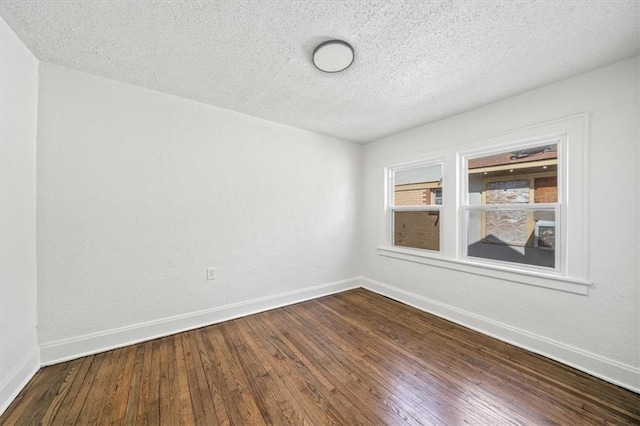 spare room with baseboards, a textured ceiling, and dark wood-style flooring