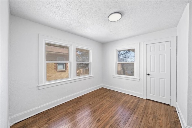 unfurnished room with baseboards, a textured ceiling, and dark wood finished floors