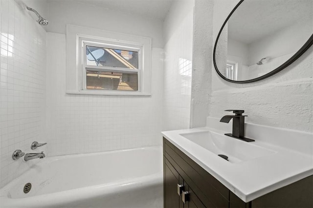 full bath featuring vanity, washtub / shower combination, and a textured wall