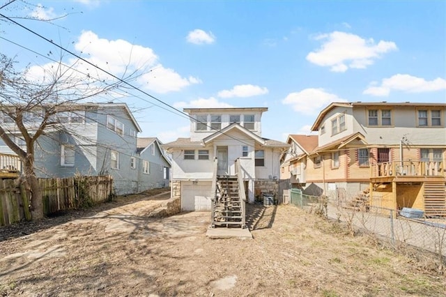 rear view of property with a residential view, fence private yard, stairs, and a garage