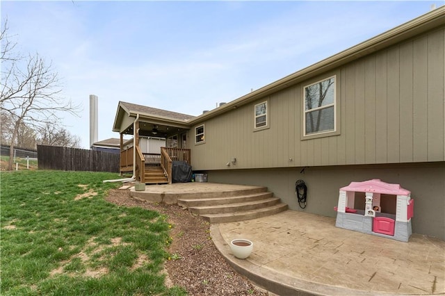 back of house with fence, a patio, a wooden deck, and a lawn