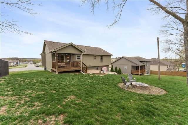 back of house featuring a yard, a wooden deck, a fire pit, and fence