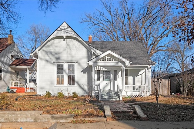 view of front of property with covered porch, a chimney, and roof with shingles