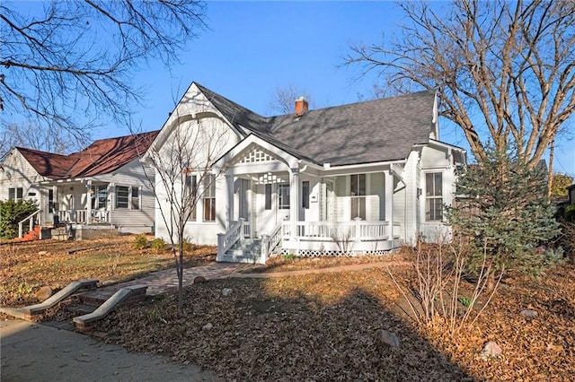 view of front of home featuring covered porch, a chimney, and a shingled roof