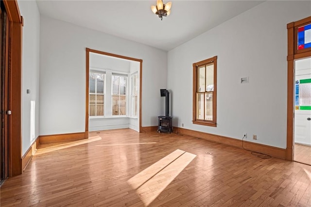 unfurnished room featuring baseboards, wood finished floors, and a wood stove