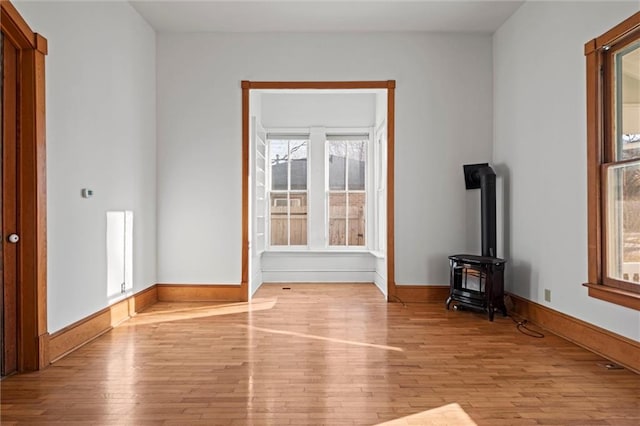 unfurnished living room featuring hardwood / wood-style flooring, a wood stove, and baseboards