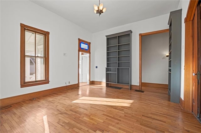 interior space featuring a notable chandelier, light wood-type flooring, and baseboards