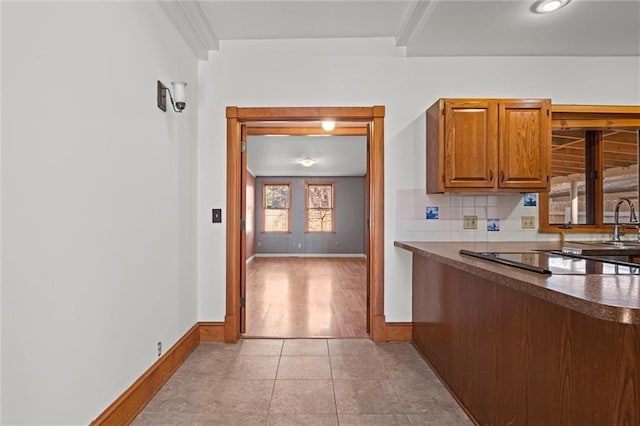 kitchen with light tile patterned floors, baseboards, backsplash, and dark countertops