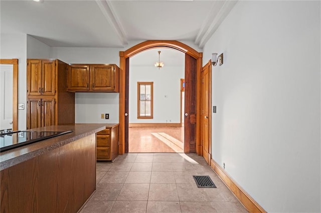 kitchen featuring light tile patterned floors, visible vents, arched walkways, dark countertops, and black electric cooktop