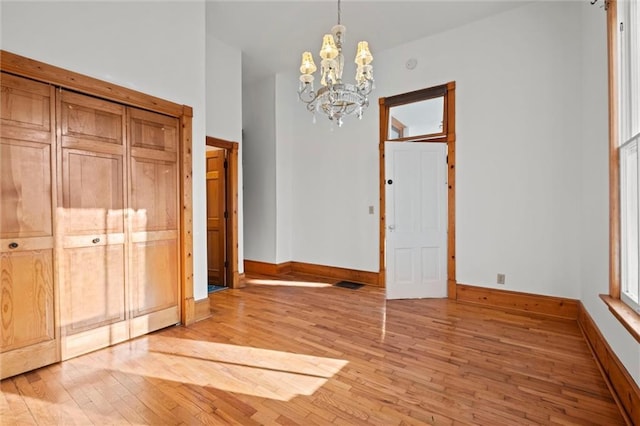 unfurnished dining area with visible vents, baseboards, light wood-style floors, and an inviting chandelier