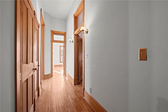 hall with light wood-type flooring and baseboards