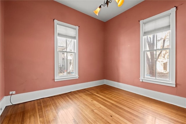 empty room with baseboards, plenty of natural light, and wood-type flooring