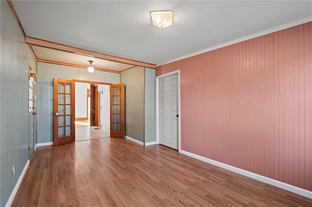 spare room with wood finished floors, crown molding, french doors, and baseboards