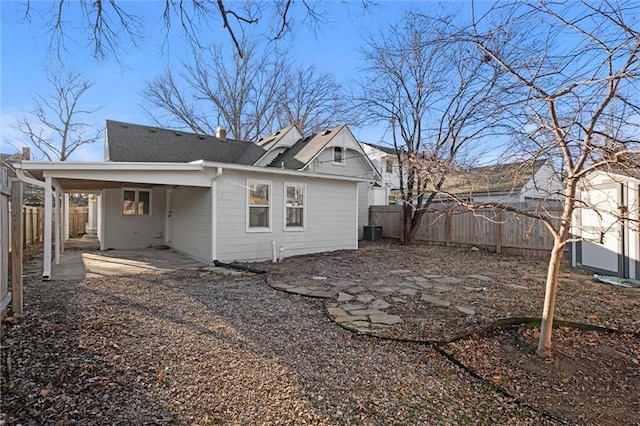 back of property featuring a carport, central air condition unit, a shingled roof, and a fenced backyard