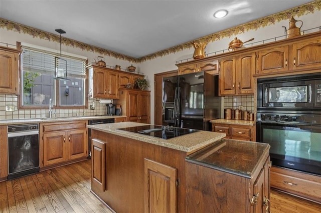 kitchen featuring a center island, a sink, brown cabinetry, and black appliances