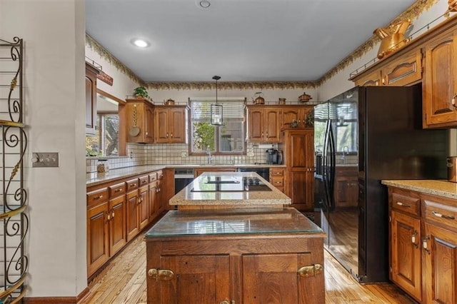 kitchen with a kitchen island, brown cabinets, light wood finished floors, and black appliances