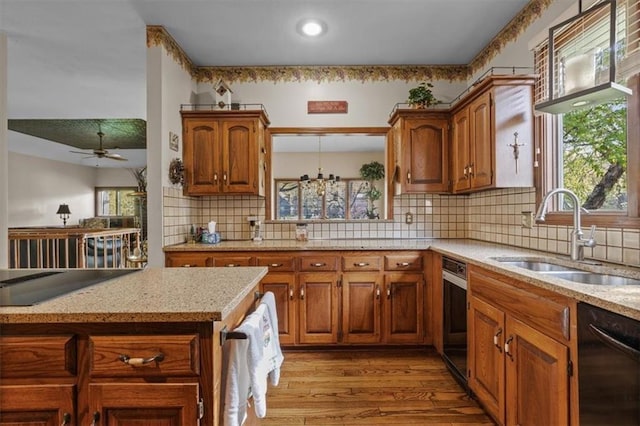 kitchen with a sink, black dishwasher, light wood-type flooring, and a wealth of natural light