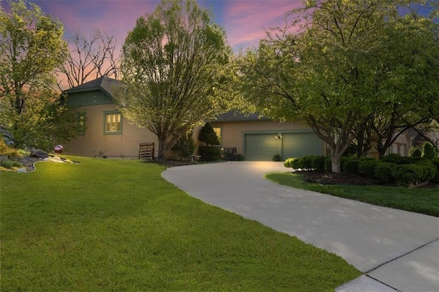 view of front of property with a garage, stucco siding, a yard, and driveway